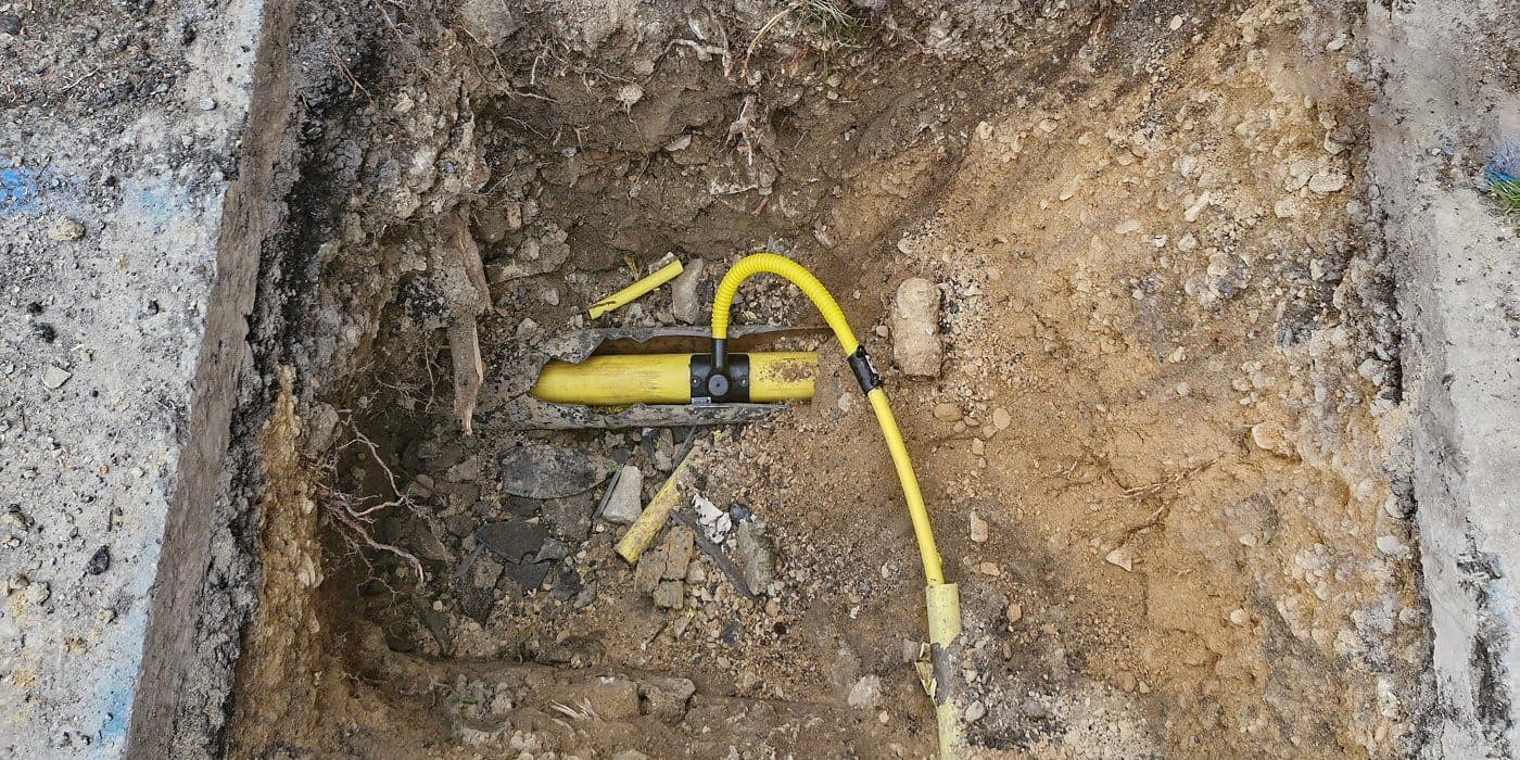 Yellow plastic gas service pipe exposed in a trench