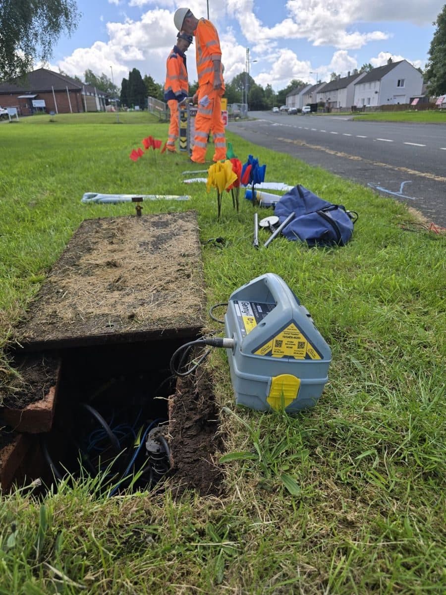 Operator locating at a communications access box, the Genny driving a signal clamp on the cable inside