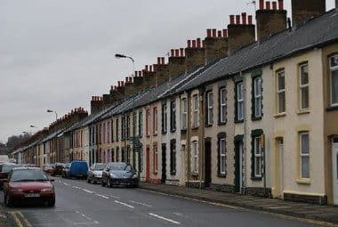 Terraced street with parked cars and lighting columns: the everyday scene a visual check has to read for clues to what is buried.