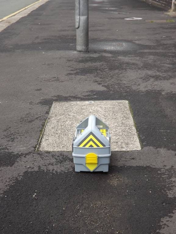 Genny upright in the centre of a paved chamber cover in the footway.
